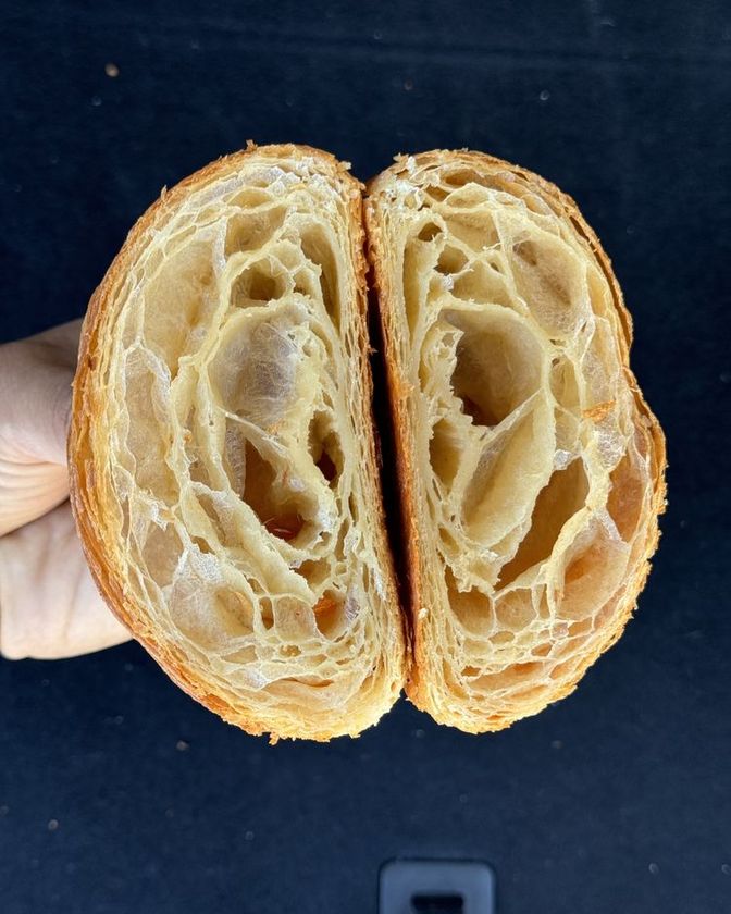 A croissant cut in half, showing its open honeycomb crumb