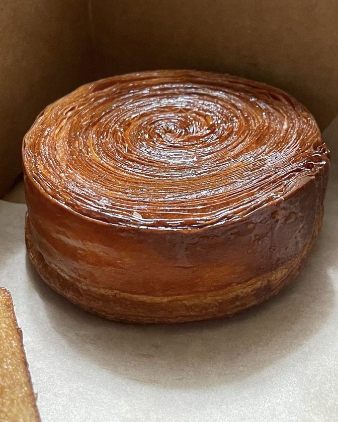 Kouign amann with a deep caramelized spiral top, in a kraft box