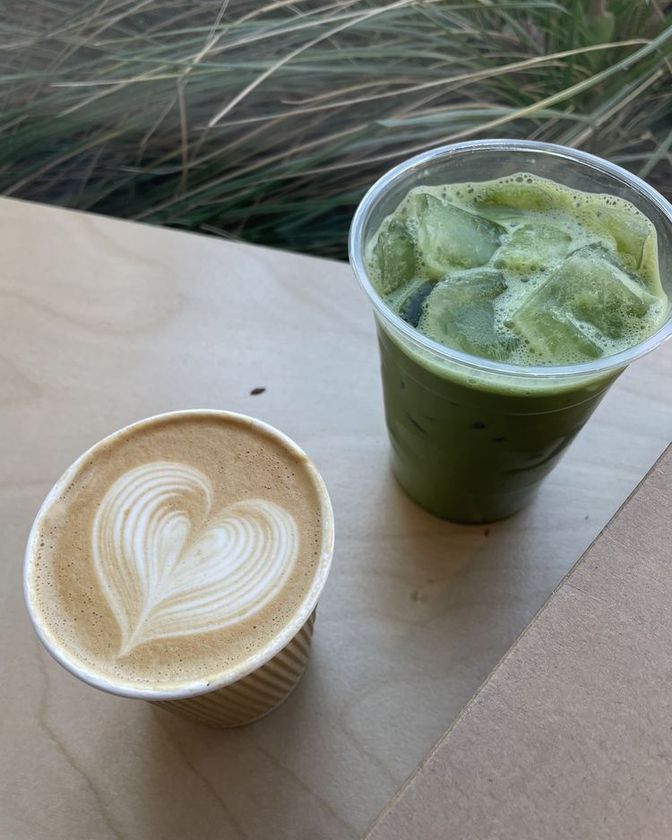 Iced matcha latte in a cup beside a hot latte with heart latte art