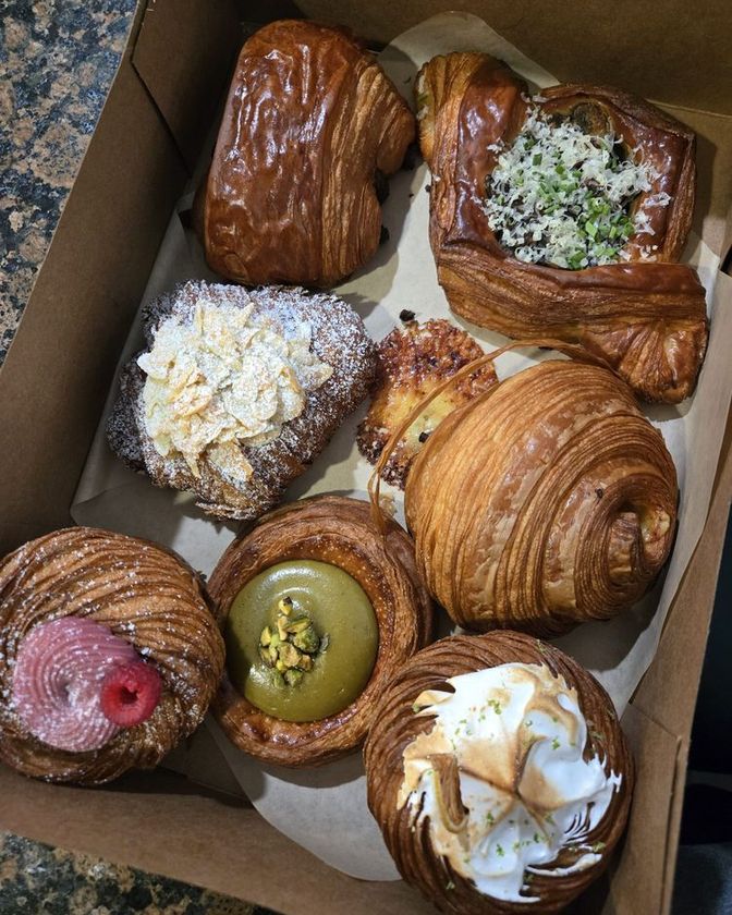 Open kraft box packed with eight pastries, from croiffins and danishes to laminated staples